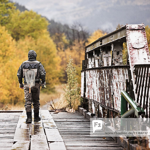 Kaukasischer Mann mit Angelrute auf einer Brücke