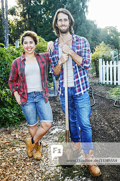 Porträt eines Paares  das mit einer Schaufel im Garten posiert