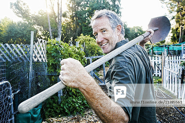 Portrait of Caucasian man carrying shovel in garden
