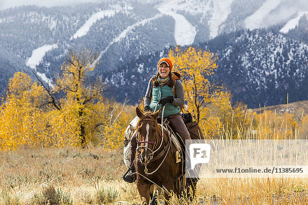 Lachende kaukasische Frau auf einem Pferd im Winter