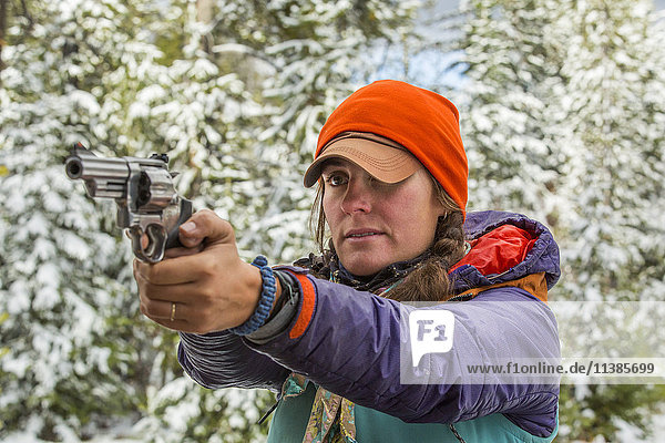Kaukasische Frau  die im Winter mit einer Handfeuerwaffe zielt