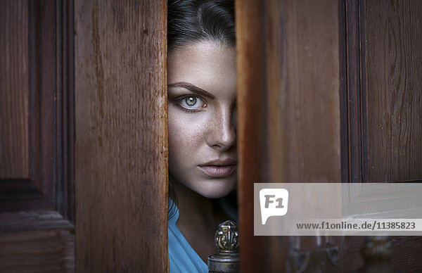 Kaukasische Frau späht durch die Tür