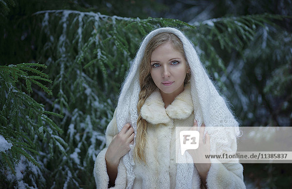 Caucasian woman wearing fur coat in snowy forest