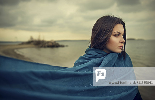 Wind weht blaue Decke der kaukasischen Frau am Strand