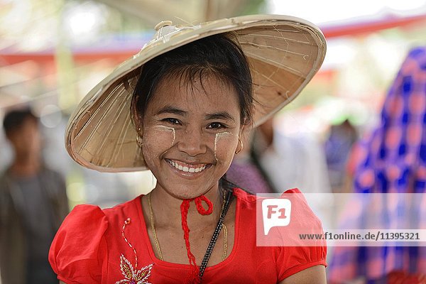 Einheimische Frau mit Strohhut und Thanaka-Paste im Gesicht  lächelnd  Mandalay  Myanmar  Asien
