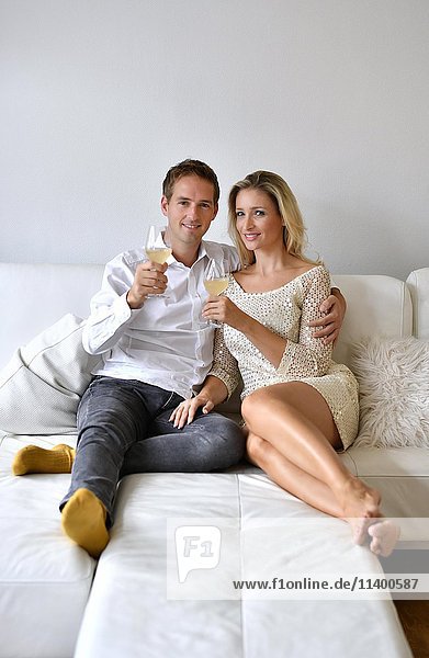 Mann  Frau  Paar auf Sofa  verliebt  Wein  Glas  in die Kamera schauen