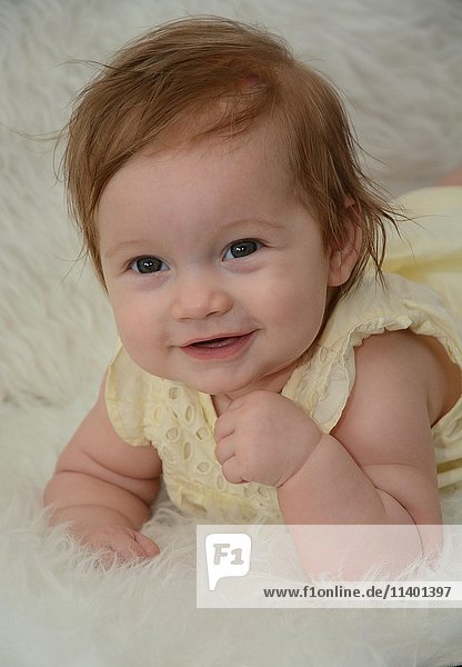 Portrait eines lächelnden Babys sechs Monate alt liegt auf weißem Fell Schweden Europa