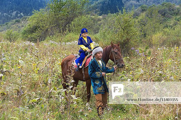 Kazakh man walking around with his son on a horse after Circumcision Sundet Toi ceremony  Kazakh ethnographic village aul Gunny  Talgar  Almaty  Kazakhstan  Asia