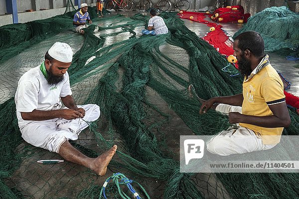 Local men repairing fishing nets in hall at harbour  Beruwela  Western Province  Sri Lanka  Asia