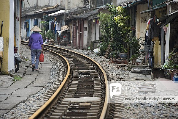 Frau mit Strohhut geht in der Nähe von Bahngleisen  Hanoi  Vietman