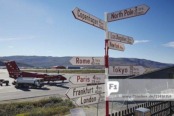 Sign post at the airport with Air Greenland plane on tarmac  Kangerlusuaq  Greenland  North America