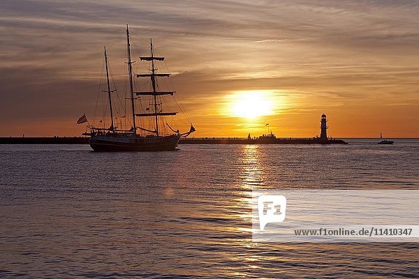 Sonnenuntergang an der Hafeneinfahrt  beleuchtetes Segelboot  Hanse-Sail  Rostock  Mecklenburg-Vorpommern  Deutschland  Europa
