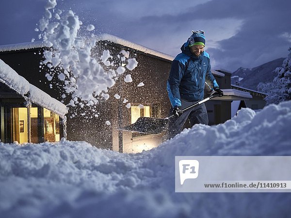 Mann  35-40 Jahre  Schneeschaufeln in der Abenddämmerung  Kolsass  Tirol  Österreich  Europa