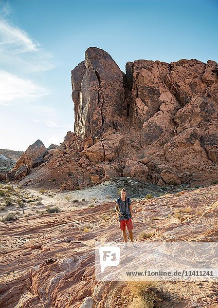 Junger Mann beim Wandern  rote Felsformationen im Abendlicht  Sandsteinfelsen  Tal des Feuers  Mojave-Wüste  Nevada  USA  Nordamerika