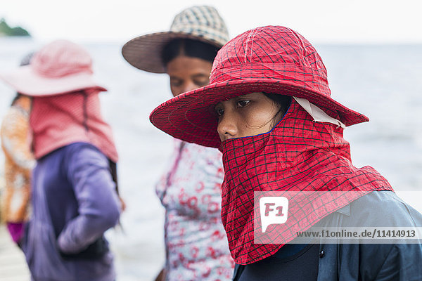 'Women wearing hats and scarves covering their mouths local life in the famous Crab Market; Kep Cambodia'