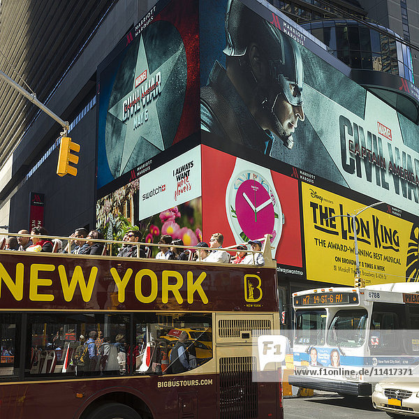 Tourbus auf einer Straße unter großen bunten Werbetafeln am Times Square; New York City  New York  Vereinigte Staaten von Amerika'.