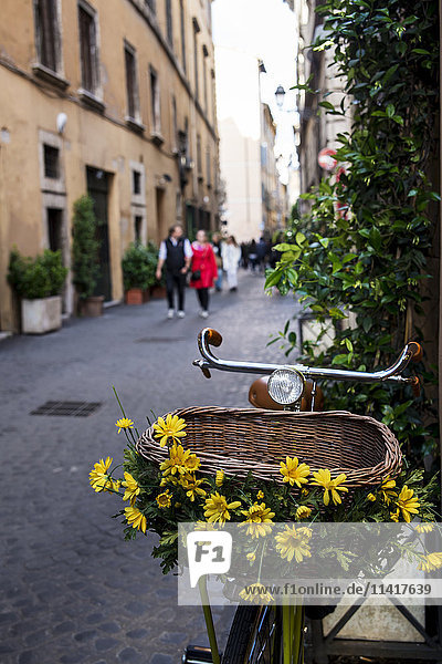 'Bike with basket decorated with flowers in a narrow street; Rome  Italy'