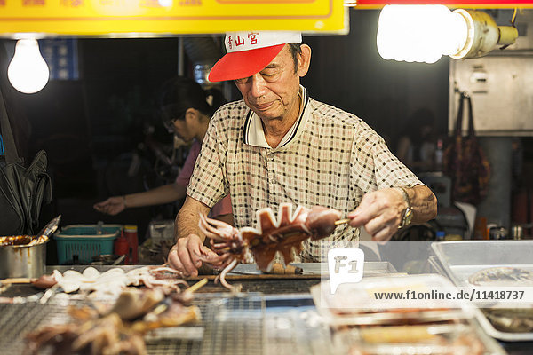 'Local night markets of Taipei are really famous because it's delicious food a male vendor preparing his specialty food; Taiwan China'