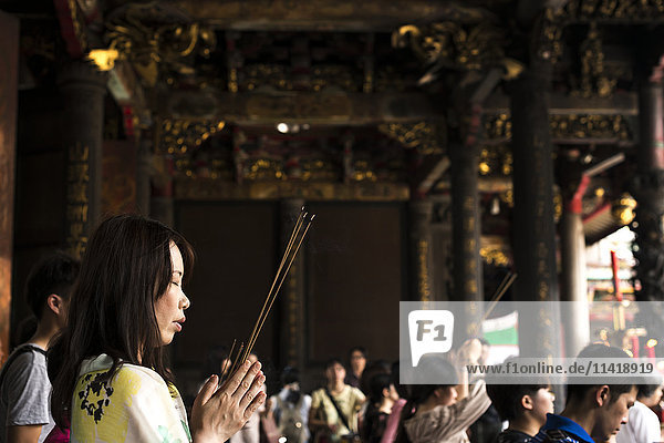 'Buddhist Longshan temple in the city center of Taipei people praying and burning incense; Taipei Taiwan China'