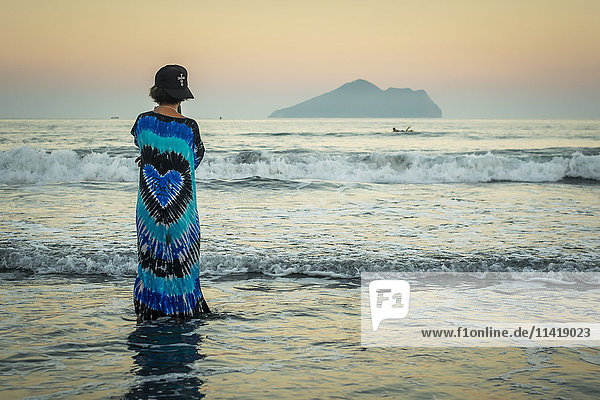 'A young woman looking out to the horizon Waiao beach in Yilan Country beautiful volcanic beach; Taiwan China'