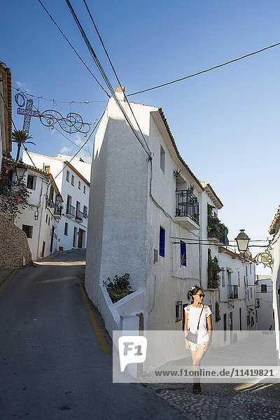 'A Chinese young woman walking on the street of the beautiful town of Altea in Costa Blanca; Altea  Alicante  Spain'