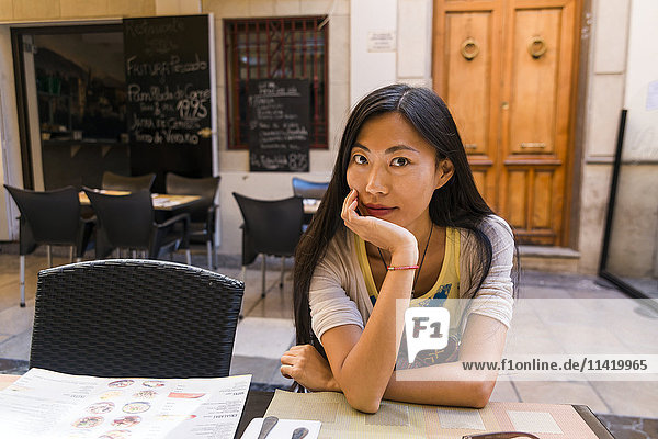 Eine chinesische junge Frau sitzt in einem Restaurant; Spanien
