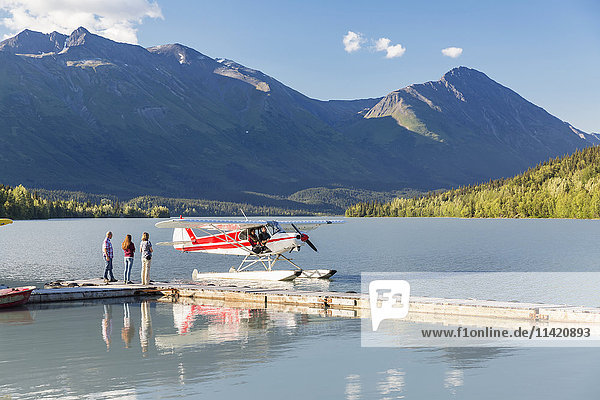 Visitors wait for the pilot to dock while  Trail Lake Float Plane Base  Moose Pass  Kenai Peninsula  Southcentral Alaska  USA