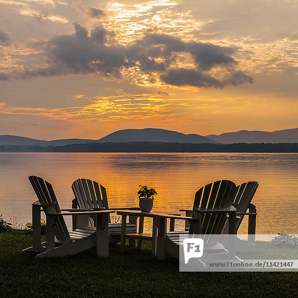 Sonnenuntergang am See mit Silhouetten von Stühlen am Kai; Knowlton,  Quebec,  Kanada'.