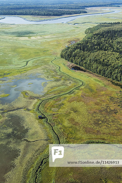 'View of the Susitna flats outside Anchorage on a charter airplane tourist flight in summertime with a duck shack sitting on the flats below; Alaska  United States of America'