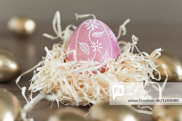 Bemaltes Osterei in einem Nest aus Holzwolle