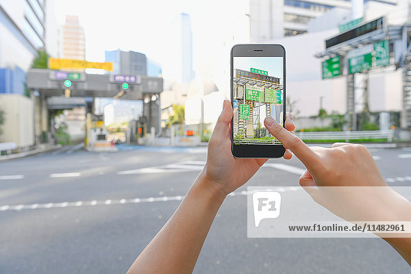 Japanese woman using augumented reality app on smartphone downtown Tokyo  Japan