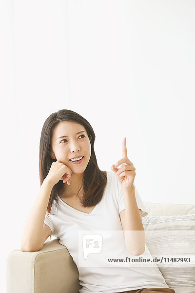 Junge japanische Frau auf dem Sofa in einem weißen Raum