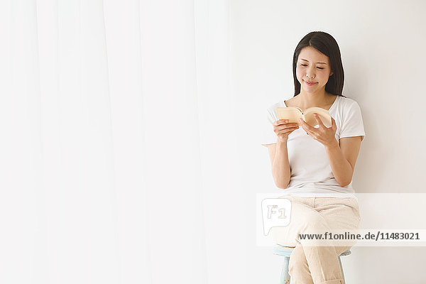 Young Japanese woman on a chair in a white room
