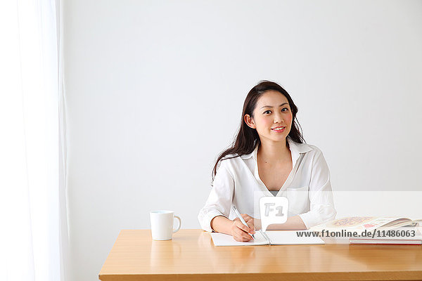 Attraktive japanische Frau sitzt an einem Tisch in einem luftigen Raum
