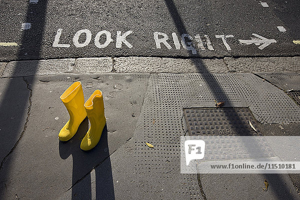 Gelbe Gummistiefel auf dem Bürgersteig