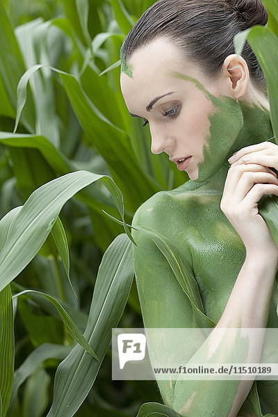 Young woman with body painting in wheat field
