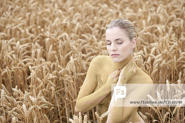 Junge Frau mit Körperbemalung in einem Weizenfeld