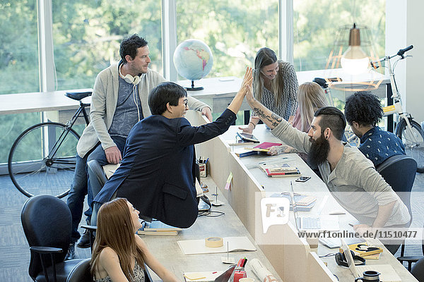 Colleagues high-fiving in casual office