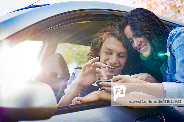 Paar sucht Wegbeschreibung auf dem Smartphone vor Fahrtantritt