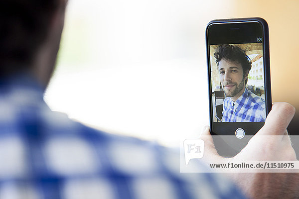 Man using smarthphone to take a selfie