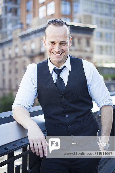 Businessman standing on balcony  smiling  portrait
