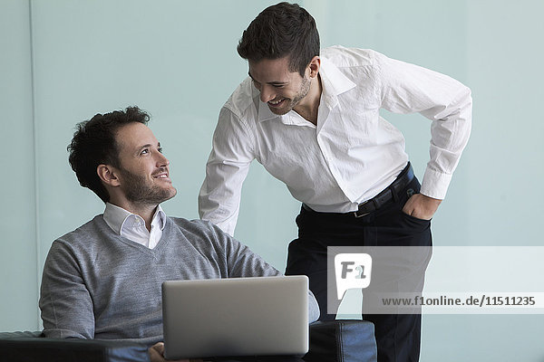 Business professionals looking at laptop computer together