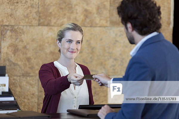 Freundliche Hotelrezeptionistin mit Kundenkreditkarte