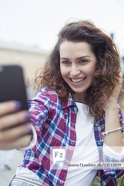 Young woman using smartphone to take a selfie