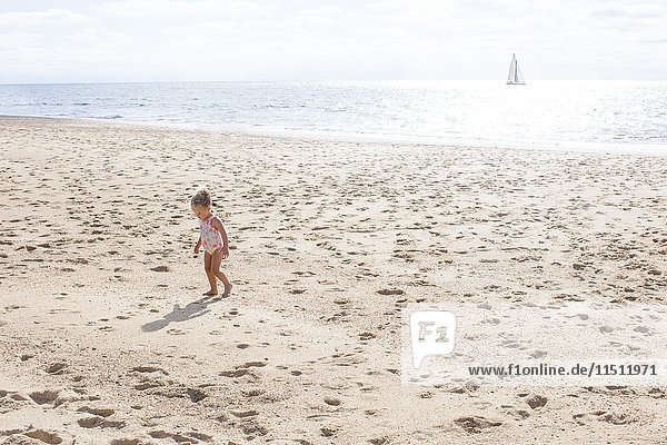 Kleines Mädchen,  das am Strand spazieren geht