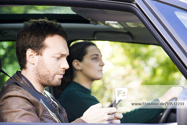 Mann beim Lesen von Textnachrichten während der Fahrt im Auto