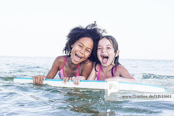 Mädchen spielen mit Bodyboard im Wasser