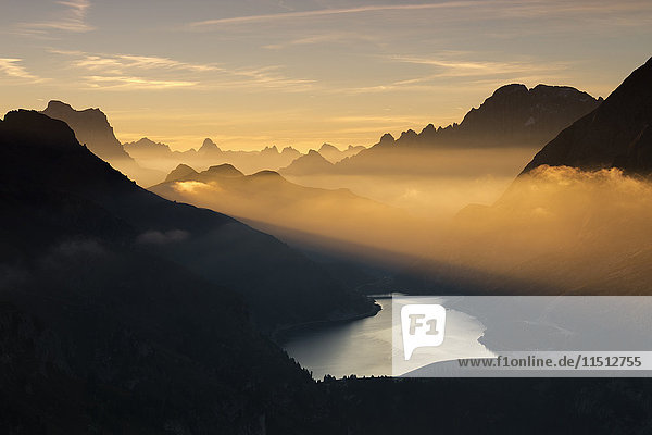 Orange light beam and mist on peaks of Dolomiti and Fedaia Pass Cima Belvedere Val di Fassa Trentino-Alto Adige Italy Europe