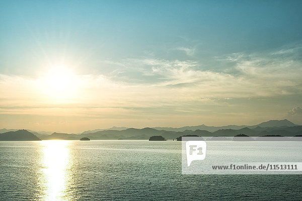 Die Sonne geht gerade über den Bergen unter  die den Qiandao-See (Tausend Inseln) umgeben  Chunan  Zhejiang  China  Asien