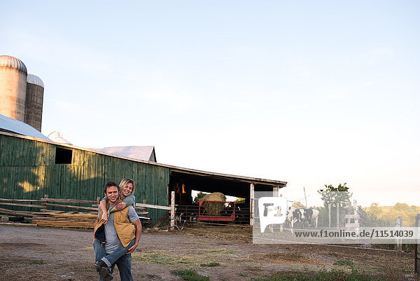 Ehepaar auf dem Bauernhof  Mann trägt Frau auf dem Rücken